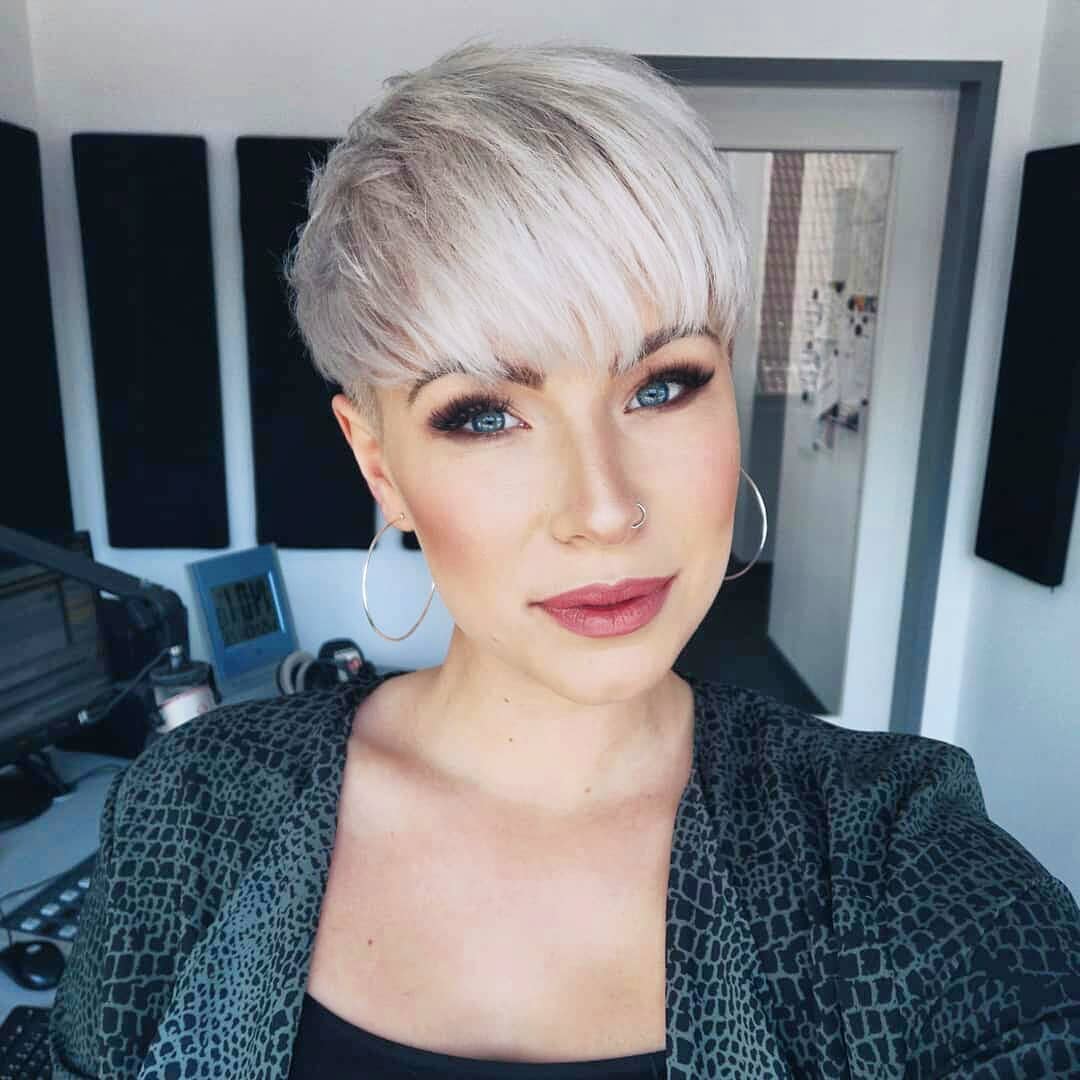 Pixie cut rasato sulla nuca e bombato, con frangia che copre tutta la fronte, in un bel biondo platino