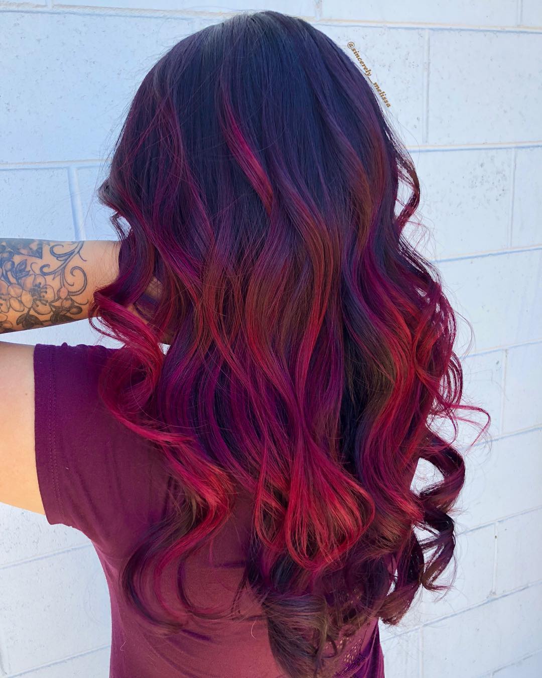 Balayage rosso cremisi e magenta su lunga chioma con styling mosso