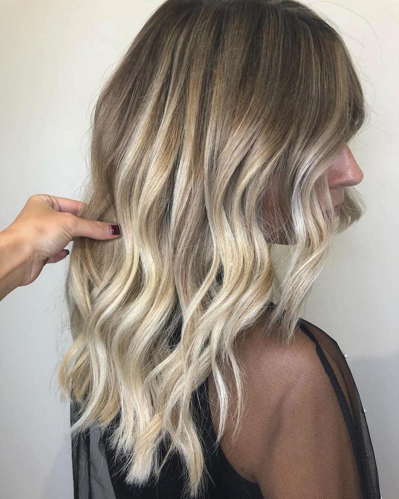 Balayage biondo su capelli lunghi e scalati con onde morbide