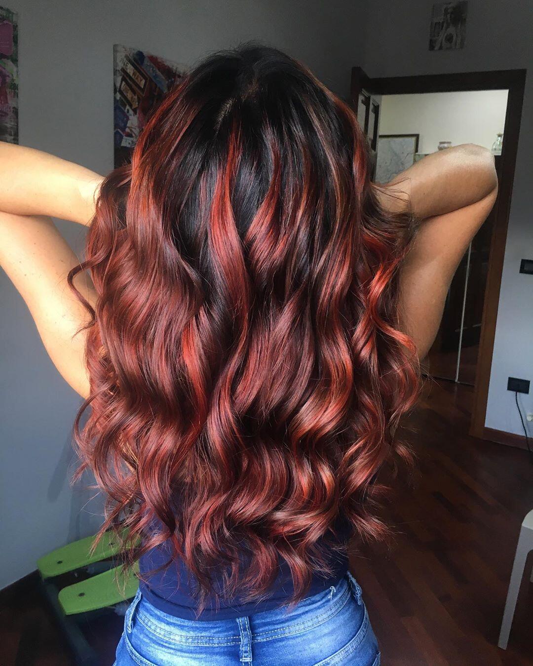 Balayage rosso luminoso su capelli lunghi e mossi